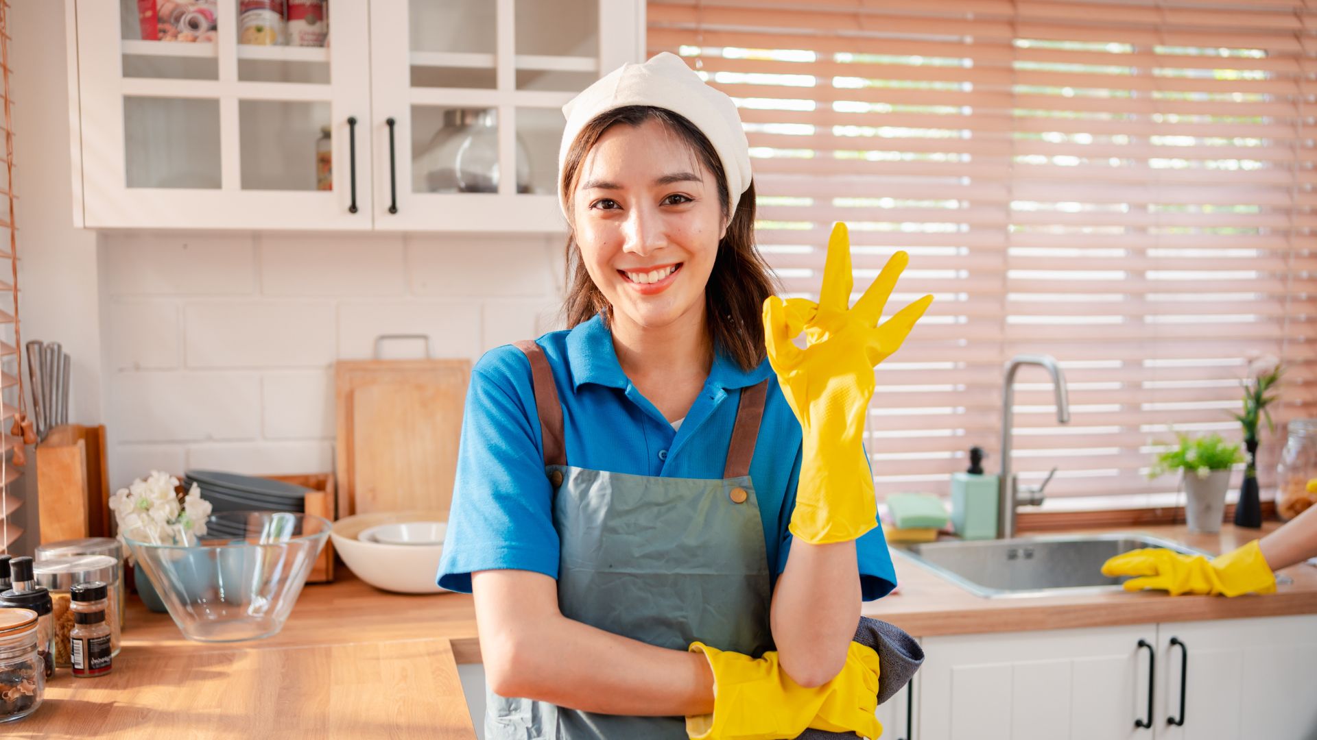 A woman in a blue shirt is holding a yellow glove