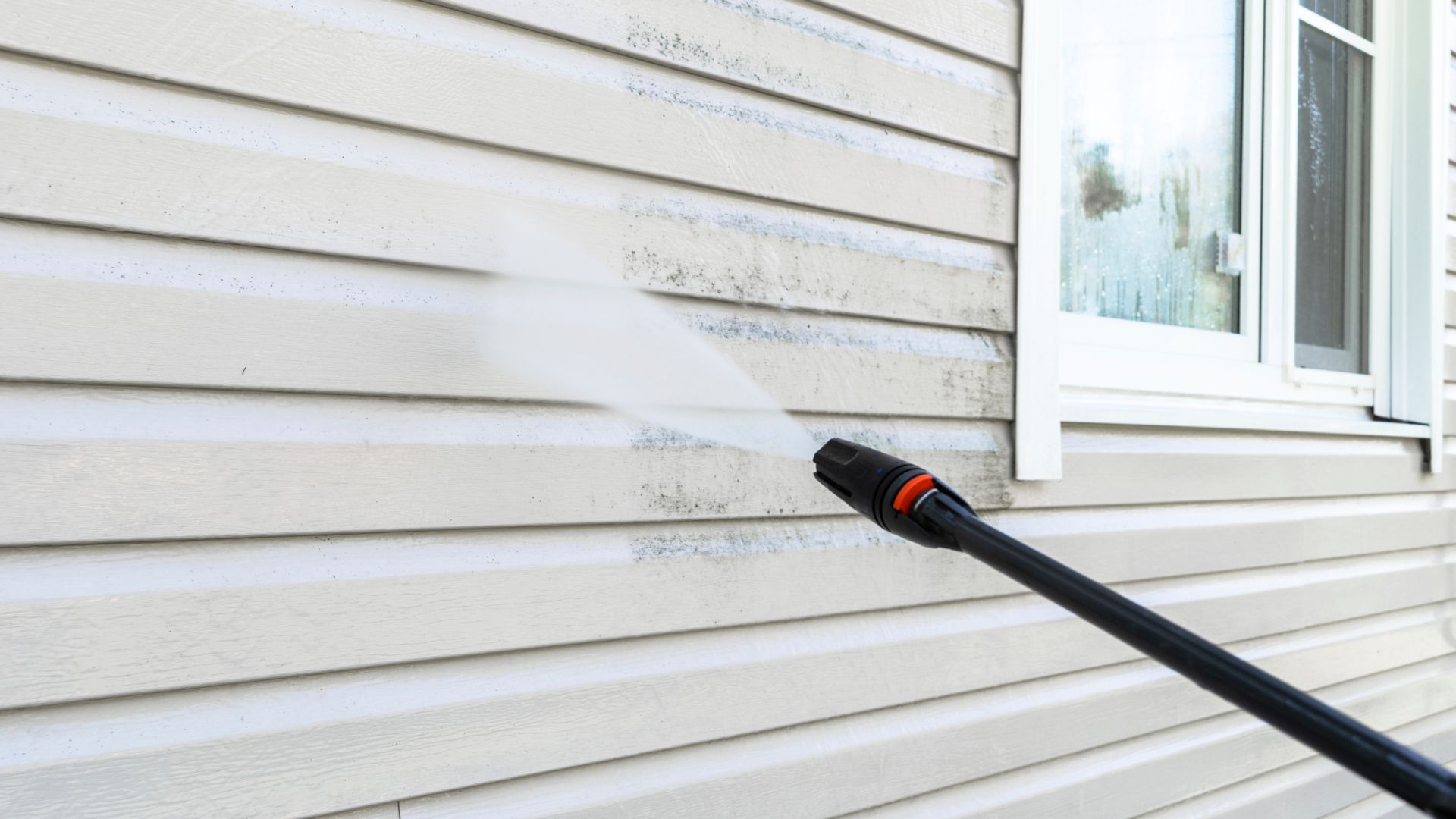 A sprayer is spraying water on the side of a house